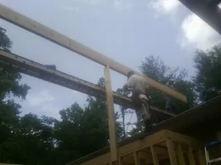 Carpenter setting a ridge beam over a new addition frame — Ice Dam Removal by Roofing Brothers in Lando
