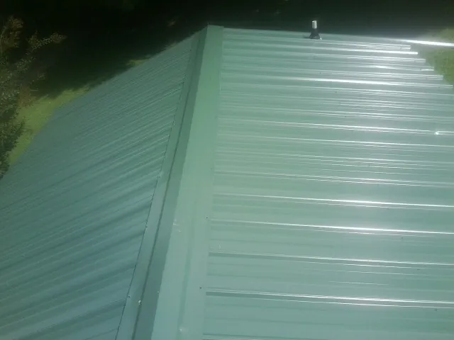 New green metal panels meeting at the ridge of a roof — Flat Roof Repair work by our crew in Lando