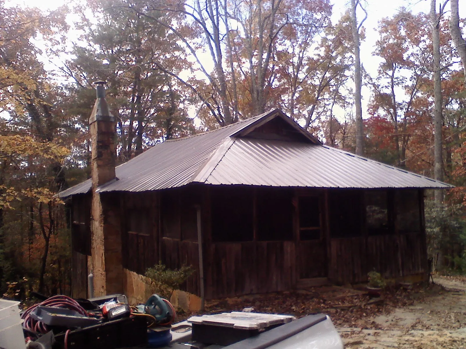 Brown metal hip roof on an old cabin with a stone chimney in Lando