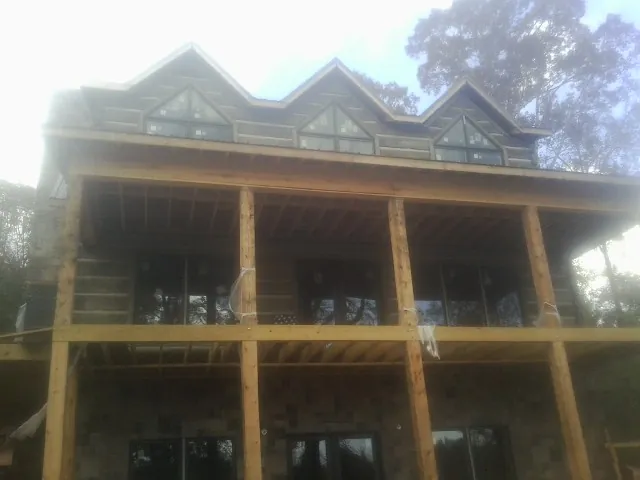 Dormers and porch framing on a large log home under construction — Roof Coating work by our crew in Lando