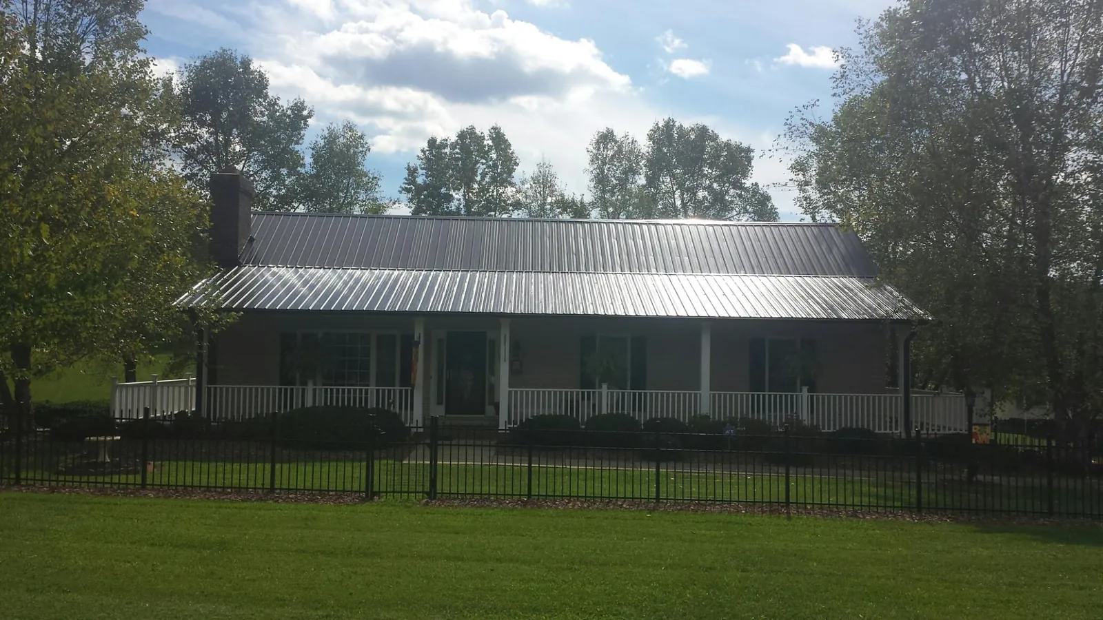 Gray metal roof on a brick ranch with a full width front porch — Gutter Guard Installation work by our crew in Lando