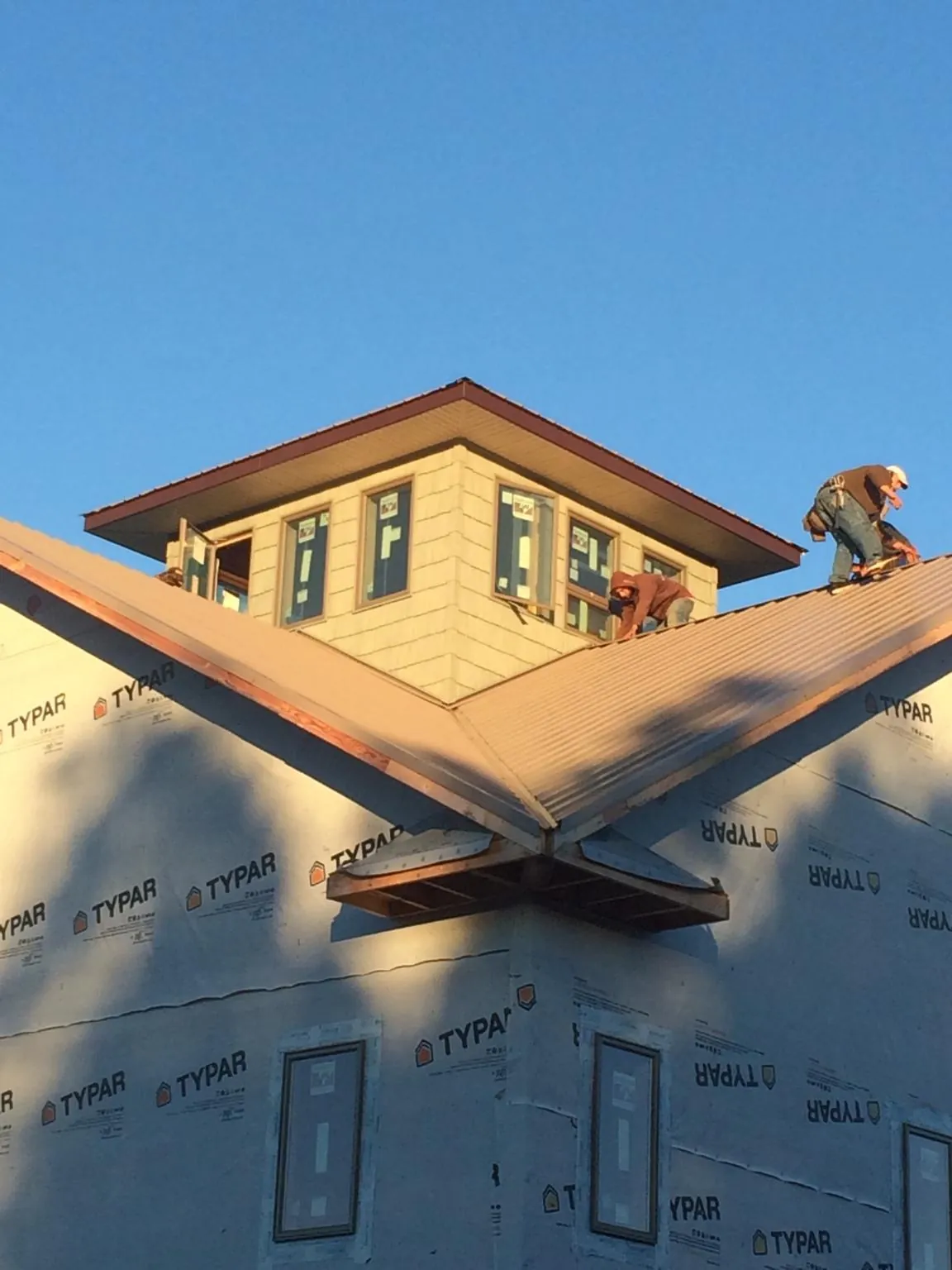 Roofers working around a rooftop cupola on a new metal roof at sunset — Roof Waterproofing in Lando by Roofing Brothers